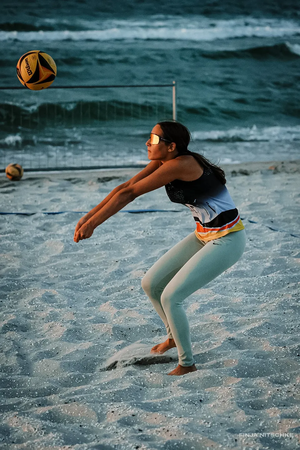 Beach volleyball player in passing position in evening light by the sea